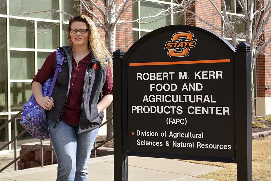 Ashley Gifford standing beside FAPC sign