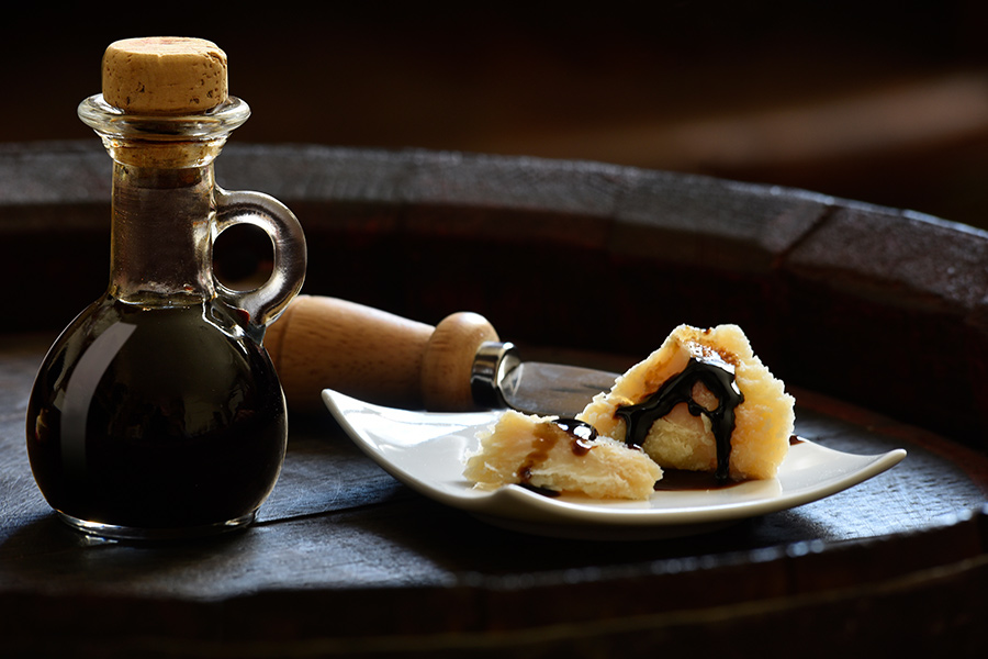 Balsamic Vinegar of Modena with Parmesan flakes set on plates and a wooden barrel